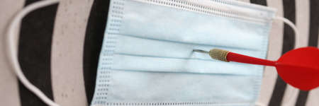 On playing darts, protective medical mask with dart in center