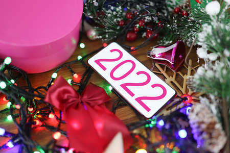 Mobile phone with 2022 on screen lying among Christmas tinsel closeup backgroundの写真素材