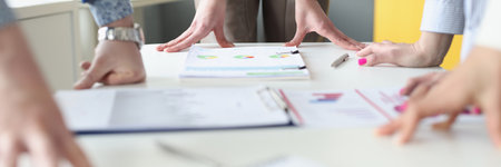 Hands of business people at work table with commercial charts