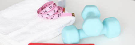 Fitness dumbbells with centimeter and towel lie on tableの写真素材