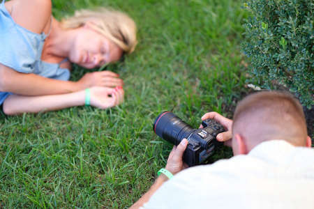 Man photographing young woman sleeping on grass