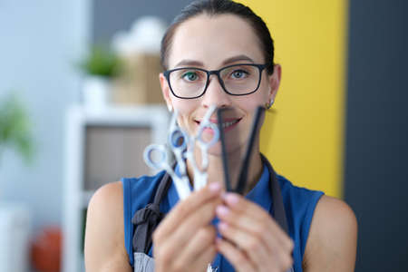 Portrait of woman hairdresser holding scissors and comb in hand. Hairdresser training conceptの写真素材