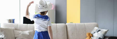 Little girl stands with her back with yellow suitcaseの写真素材