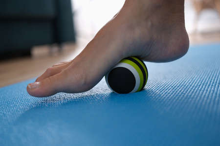 Woman leg rolling ball on foot at home closeupの写真素材