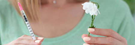 Woman beautician holding syringe with medicine and wilted flower in her hands closeupの写真素材