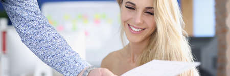 Portrait of smiling businesswoman whose colleague hands over business documentの写真素材