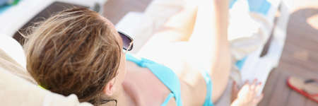 Young woman in blue bikini lies on sun lounger