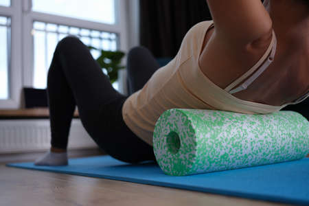 Woman doing foam roller exercises to relieve back pain closeupの写真素材