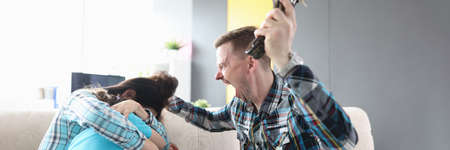 Angry man yells at his wife and child holding belt in his handの写真素材