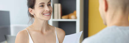 Young woman and man are sitting at table with documents in their hands at homeの写真素材