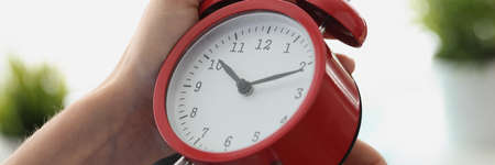 Woman hand starting red alarm clock closeupの写真素材
