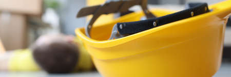 Yellow worker helmet on floor beside motionless construction workerの写真素材