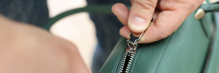 Male hands zip up green leather bag closeupの写真素材