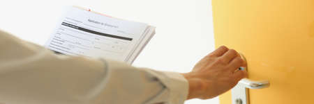 Woman knocking on door with application for employment closeup