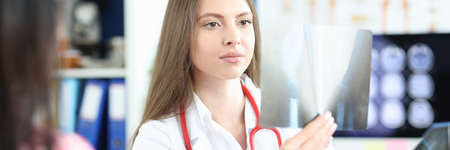 Female doctor examines x-ray from patients at reception