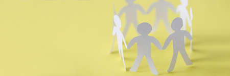 Cut paper people forming union circle on yellow backgroundの写真素材
