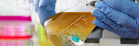 Scientist is conducting study of liquid in a yellow-brown flask