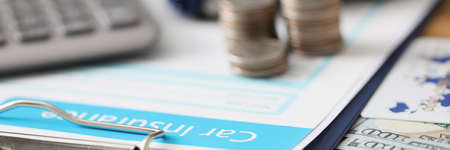 Insurance contract with coins and toy car together with calculator lie on table