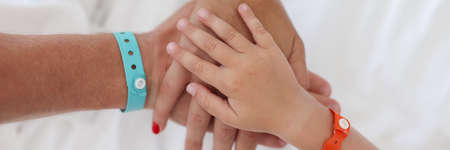 Hands of parents and child with bracelet are joined togetherの写真素材