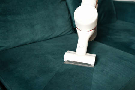 Clean fabric upholstery with white vacuum cleaner. Household appliances for cleaning furnitureの写真素材