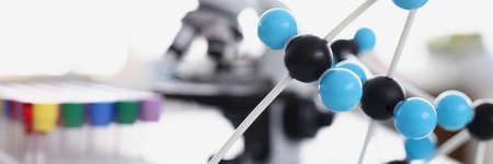 Test tubes with plastic molecules and microscope are on tableの写真素材