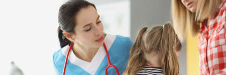 Little girl holding her neck at pediatrician doctor appointmentの写真素材