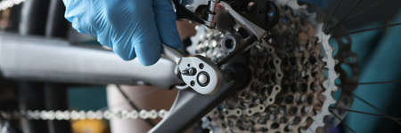 Technician in protective gloves repairing rear wheel of bicycle closeupの写真素材