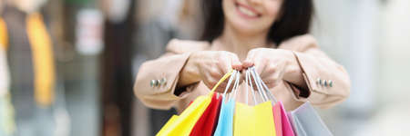 Woman holding many multicolored paper shopping bags in store closeupの写真素材