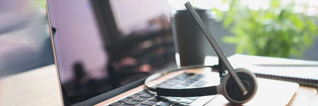 Headphones with microphone lying on laptop keyboard on desktop closeupの写真素材