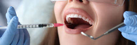 Doctor dentist making injection with anesthetic into gum of woman patient closeupの写真素材