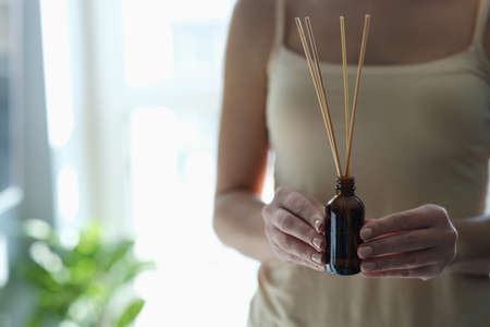 Bottle with incense sticks in female hands closeupの写真素材