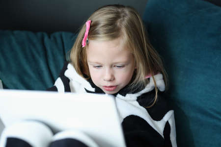 Portrait of little beautiful girl in pajamas read carefully before going to bedの写真素材