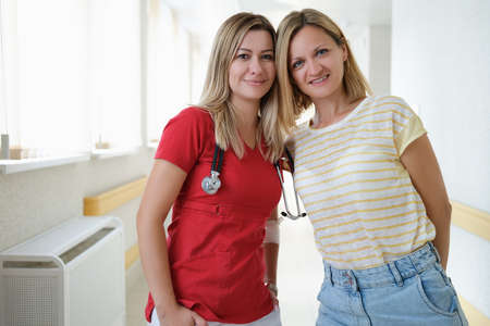 Woman doctor and patient standing in hospital corridor portraitの写真素材