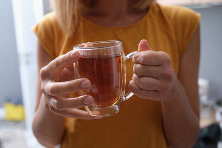 Woman holds transparent cup of hot tea in hands closeupの写真素材