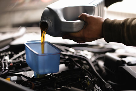 Foreman pours car oil into engine through watering can closeupの写真素材