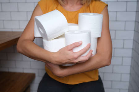 Woman holding many rolls of toilet paper in bathroom closeupの写真素材