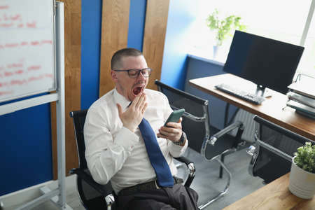 A man in the office yawns at his workplace. Procrastination.の写真素材
