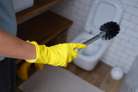 Hand in a glove holds a toilet brush, close-upの写真素材