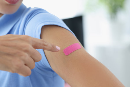 Woman showing her index finger to patch at injection site of flu vaccine closeup