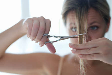 Young woman cutting off her bangs with scissors closeupの写真素材