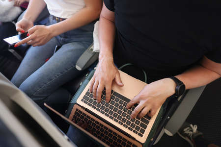 Couple using gadgets on airplane