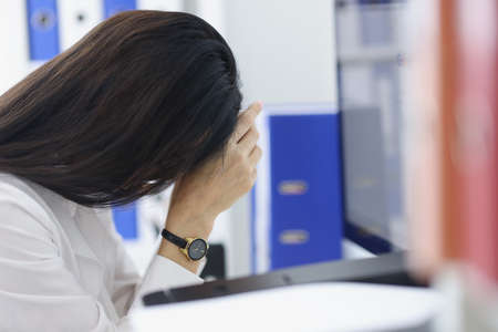 Exhausted woman in office workspaceの写真素材
