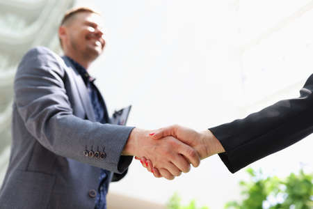 Business man and woman in suits shaking hands closeup