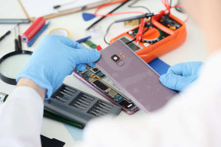 Master opening back cover of mobile phone in workshop closeupの写真素材