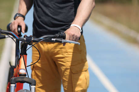 Man with mountain bike standing on bicycle path closeup