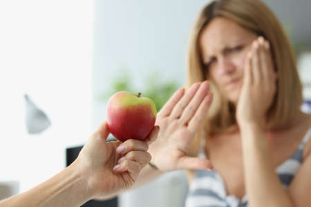Person give apple to friend and woman refuse to eat because of tooth painの写真素材