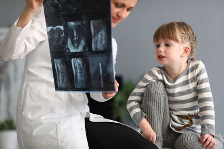 Woman doctor shows little girl an X-ray of spineの写真素材