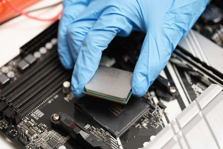 A hand in gloves holds a microcircuit over the device