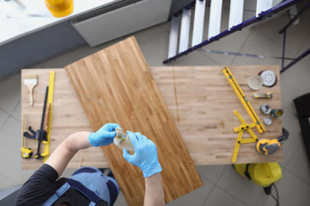 Worker at construction preparing to cover wooden plank with polish