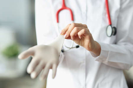 Doctor or nurse putting on sterile gloves before work in clinicの写真素材